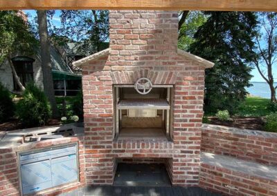 Outdoor brick wood fire grill with hand crank adjustable grill